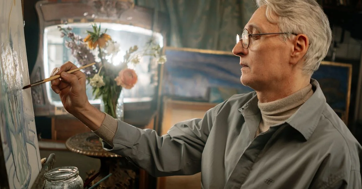 Un artiste âgé profondément engagé dans la peinture dans son studio, créant des œuvres d'art vibrantes.