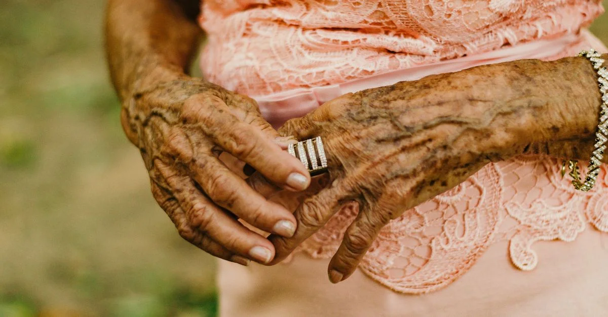 Gros plan détaillé des mains d'une femme âgée ornées de bagues et de bracelets, mettant en valeur la beauté du vieillissement.