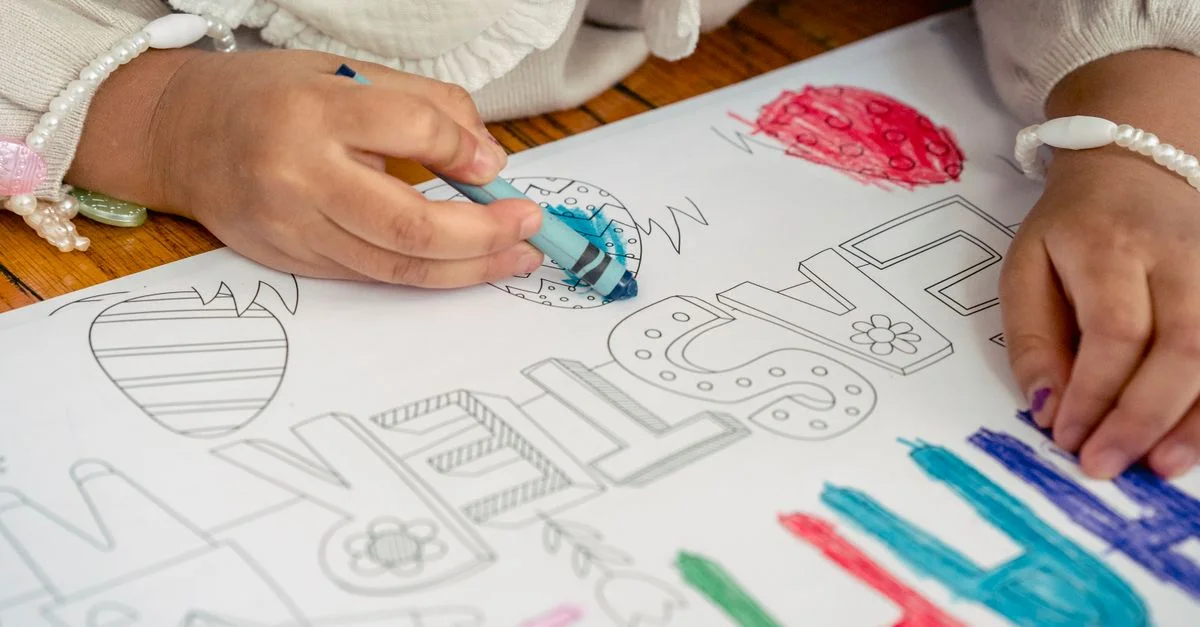 Jeune enfant coloriant des dessins sur le thème de Pâques avec des crayons, mettant l'accent sur la créativité et le plaisir.