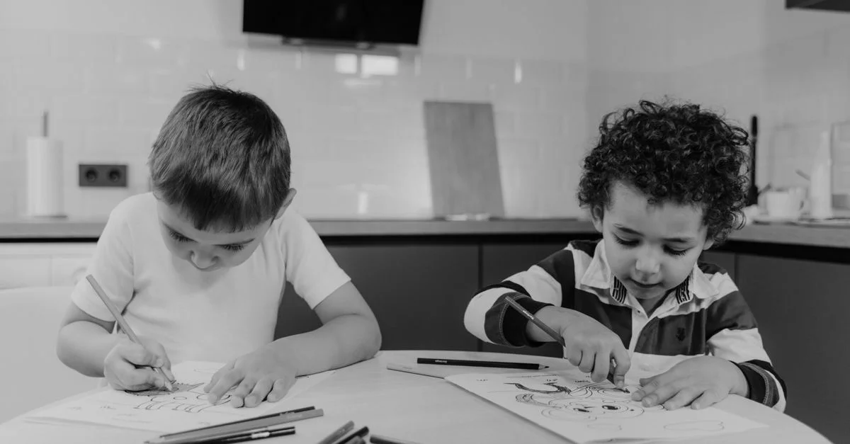 Deux enfants engagés dans des activités créatives de dessin à l'intérieur avec des crayons.