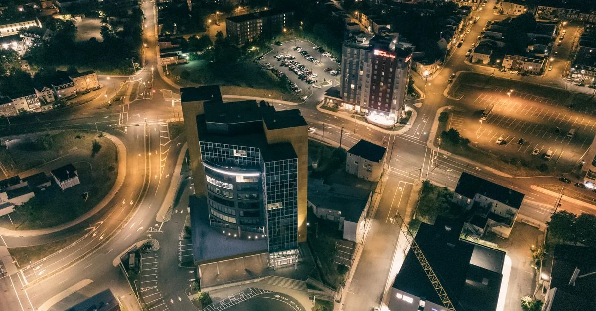 La photographie aérienne de nuit capture les rues et les bâtiments illuminés d'une ville, mettant en avant la vitalité urbaine.