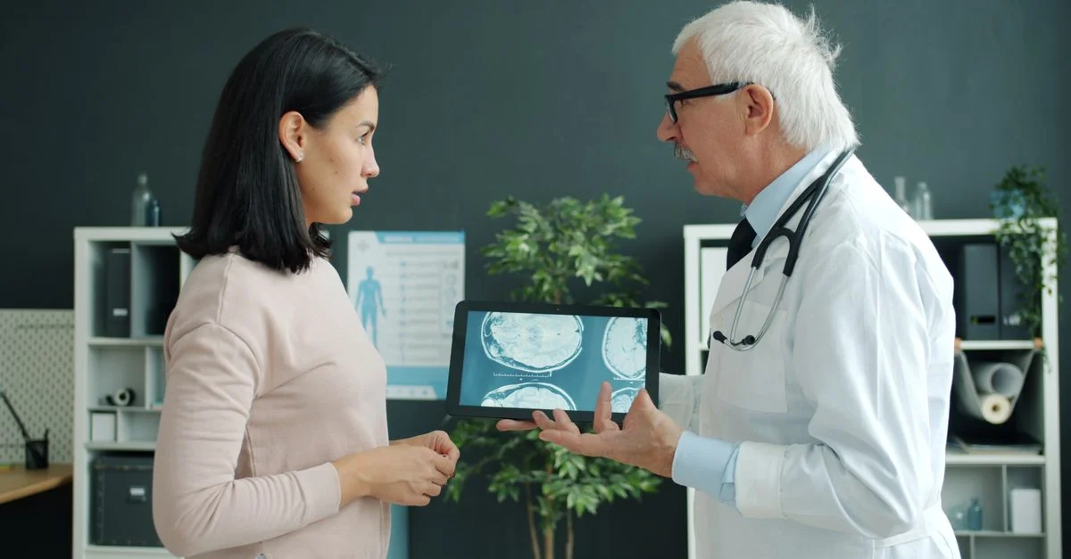 Un médecin montre à une patiente des images IRM cérébrales dans un cadre clinique, lors d'une consultation.
