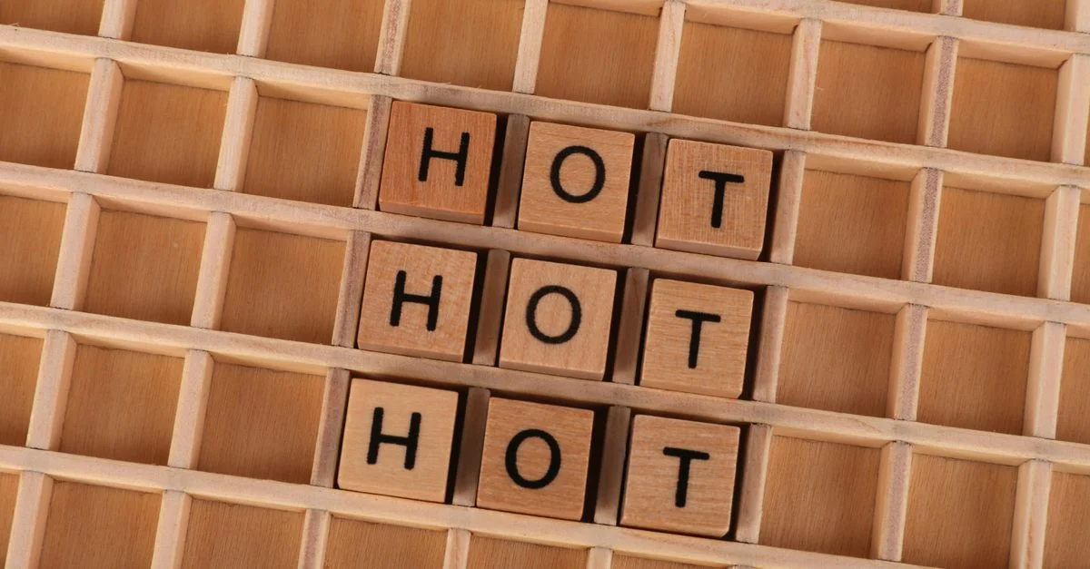 Des lettres en bois forment le mot « HOT » sur un fond de grille en bois.