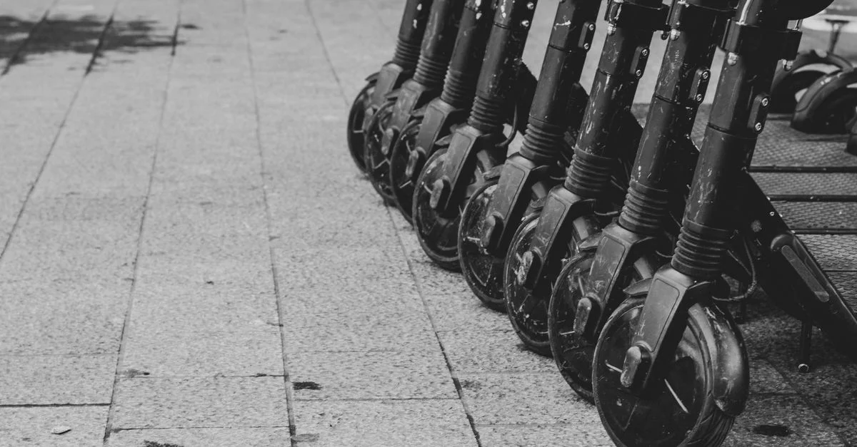 Photo en noir et blanc de scooters électriques alignés sur le pavé à Bruxelles.