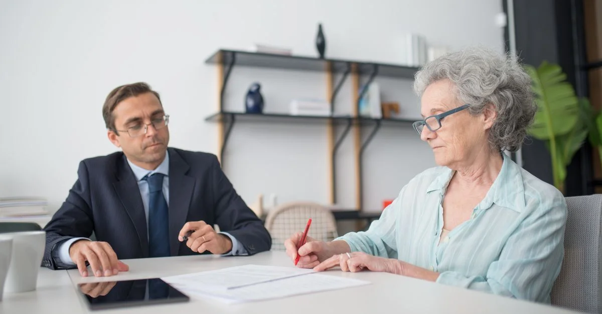 Femme âgée signant des papiers dans un bureau moderne avec un consultant.