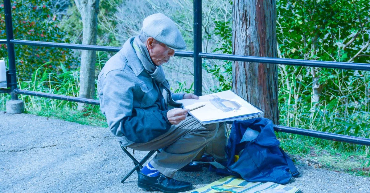 Homme senior esquissant en plein air à Kyoto, capturant la nature sereine avec un focus artistique.