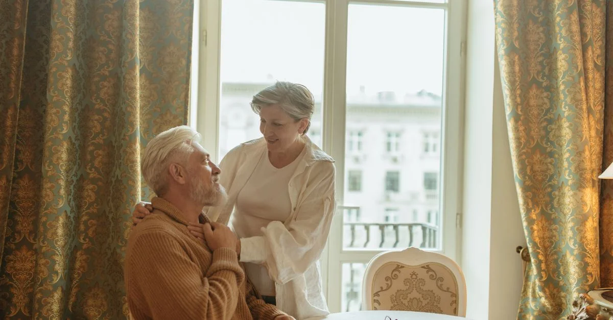 Couple âgé profitant d'un moment sincère à la maison, incarnant soin et complicité.