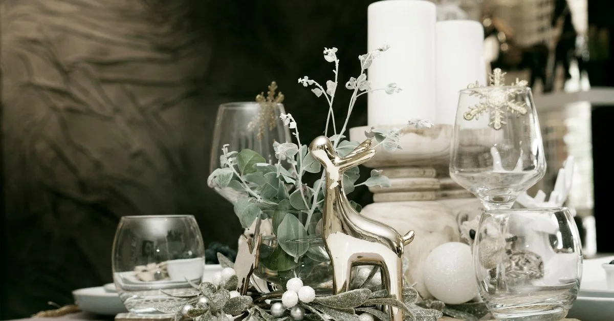 Mise en place de table de Noël élégante avec des rennes décoratifs, des bougies et de la verrerie festive pour un rassemblement chaleureux.