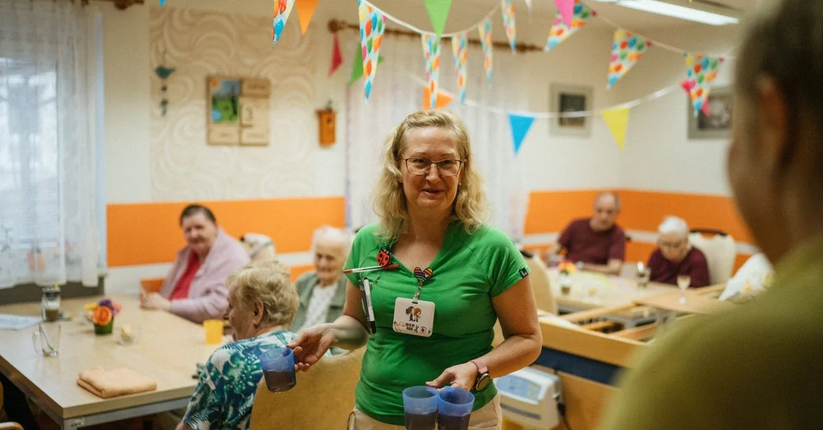 Un aide-soignant servant des boissons aux résidents âgés dans une ambiance joyeuse de maison de retraite.
