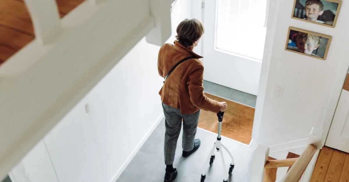 Une personne âgée marchant à l'intérieur avec un rollator, illustrant l'indépendance et la mobilité.