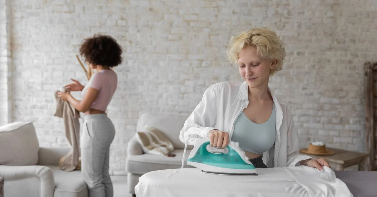 Deux femmes s'occupant du repassage et du pliage du linge à la maison, appréciant les tâches ménagères ensemble.
