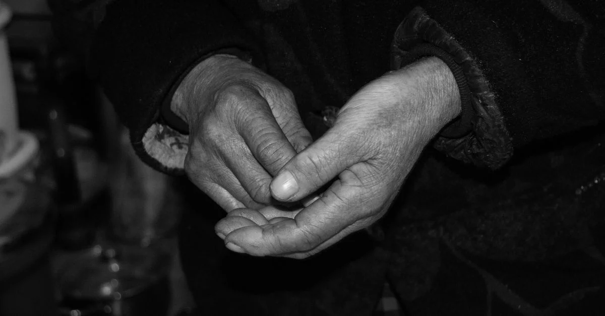Gros plan de mains âgées, patinées et expressives, capturées en noir et blanc.