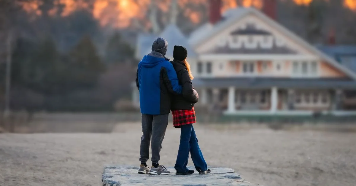 Un couple en vêtements d'hiver profitant d'un paisible coucher de soleil sur la plage.