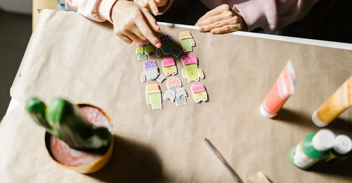 Des mains arrangeant des découpes de papier colorées sur une table, mettant en avant la créativité et les compétences en bricolage.