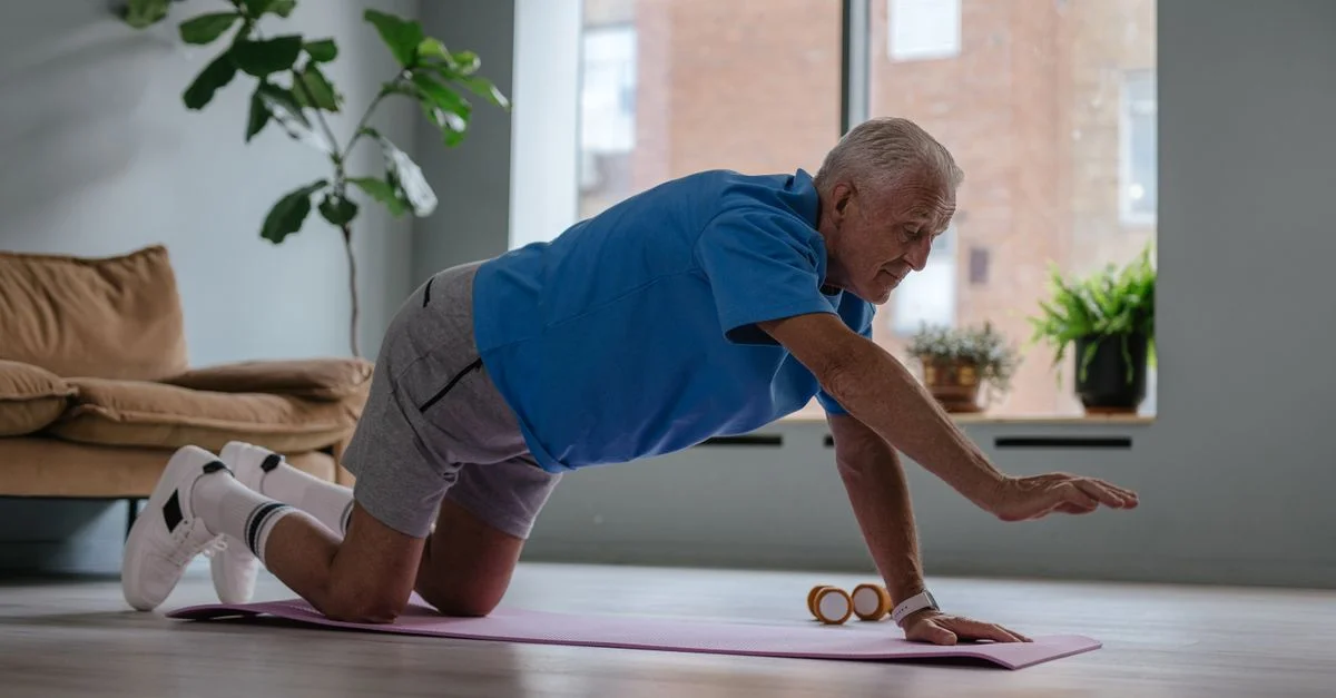 Homme âgé faisant de l'exercice sur un tapis de yoga à la maison, promouvant un mode de vie sain et le bien-être.