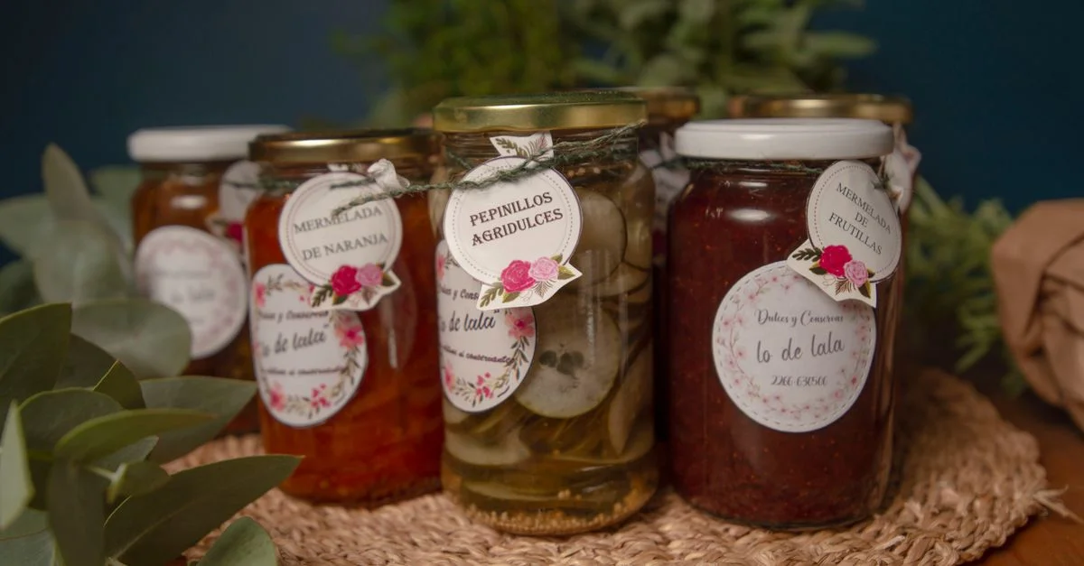 Une collection de confitures et pickles artisanaux faits maison dans des pots en verre avec des étiquettes florales.