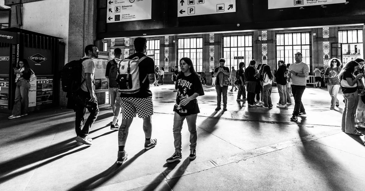 Photo en noir et blanc capturant des personnes marchant à l'intérieur de la gare de Sao Bento à Porto, Portugal.