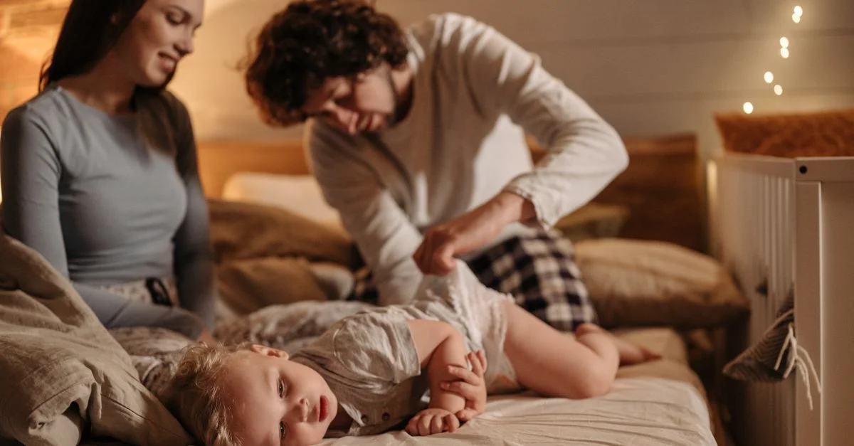 Les parents profitent d'un moment de complicité avec leur bébé pendant le changement de couche dans un cadre de chambre confortable.
