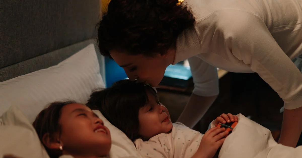 Une femme embrasse deux enfants pour leur souhaiter bonne nuit, favorisant chaleur et confort pour un coucher paisible.