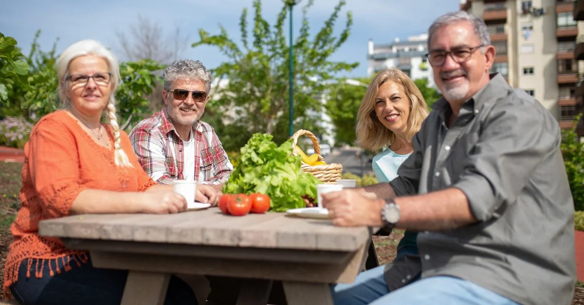 Groupe heureux de seniors profitant d'un pique-nique en plein air avec des légumes frais.