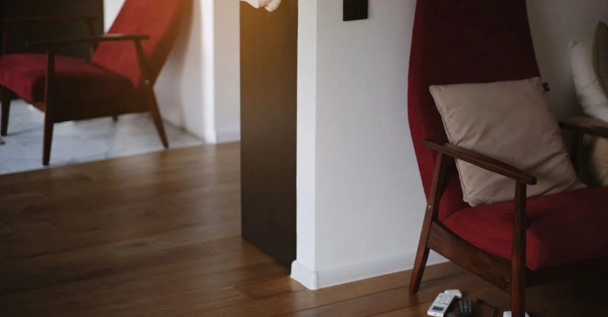 Fauteuil rouge élégant avec des pieds en bois dans un salon minimaliste chaleureux.