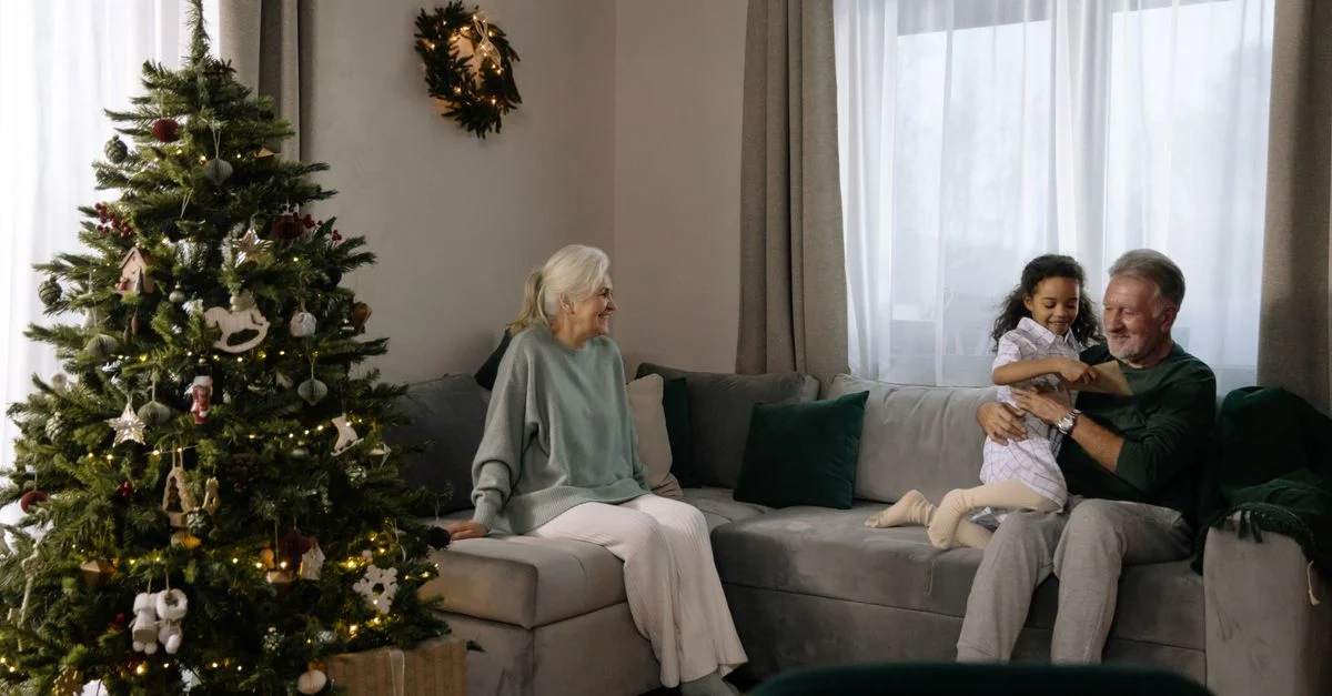 Couple âgé avec petit-enfant près du sapin de Noël profitant des fêtes ensemble.