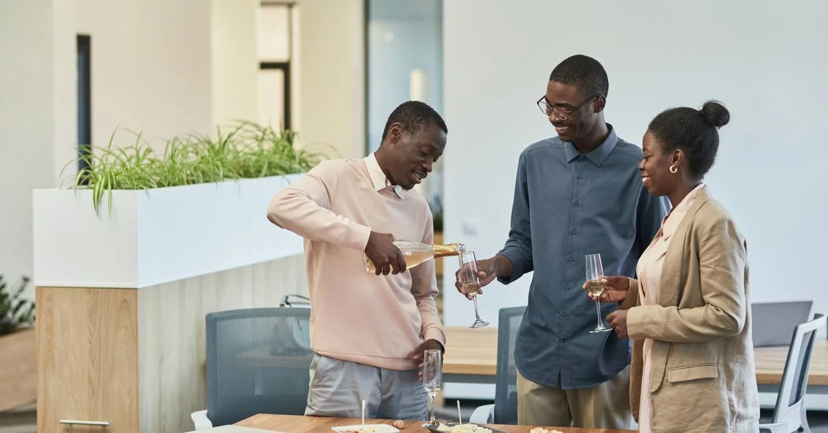 Trois collègues font un toast de célébration avec du champagne dans un cadre de bureau moderne.