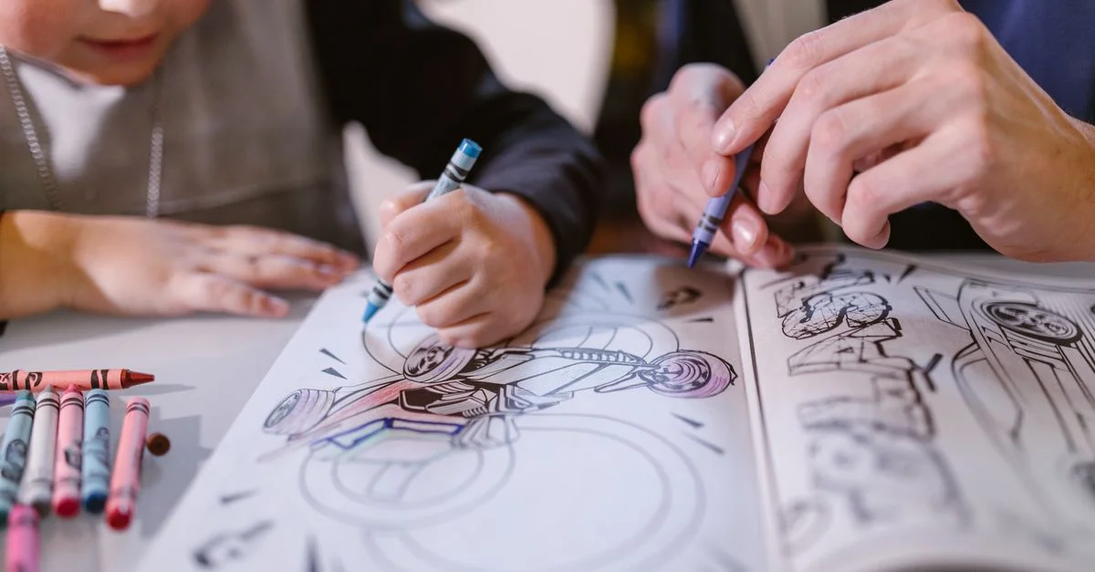 Un enfant et un adulte colorient une image de motard dans un livre de coloriage, utilisant des crayons.