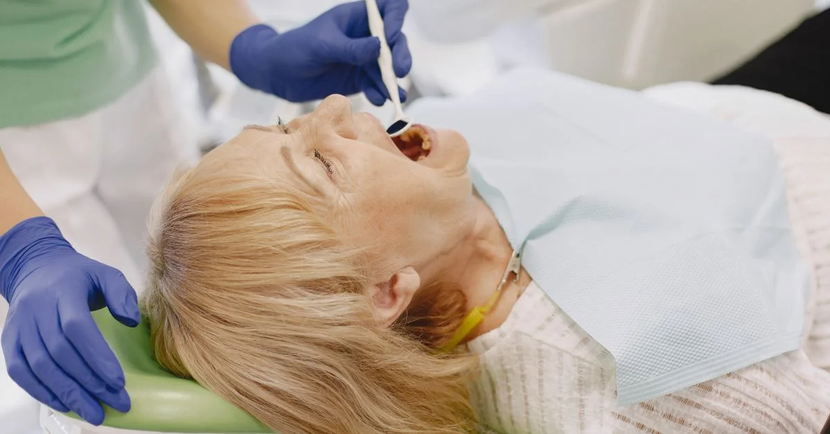 Femme âgée subissant un examen dentaire par un dentiste portant des gants dans une clinique.