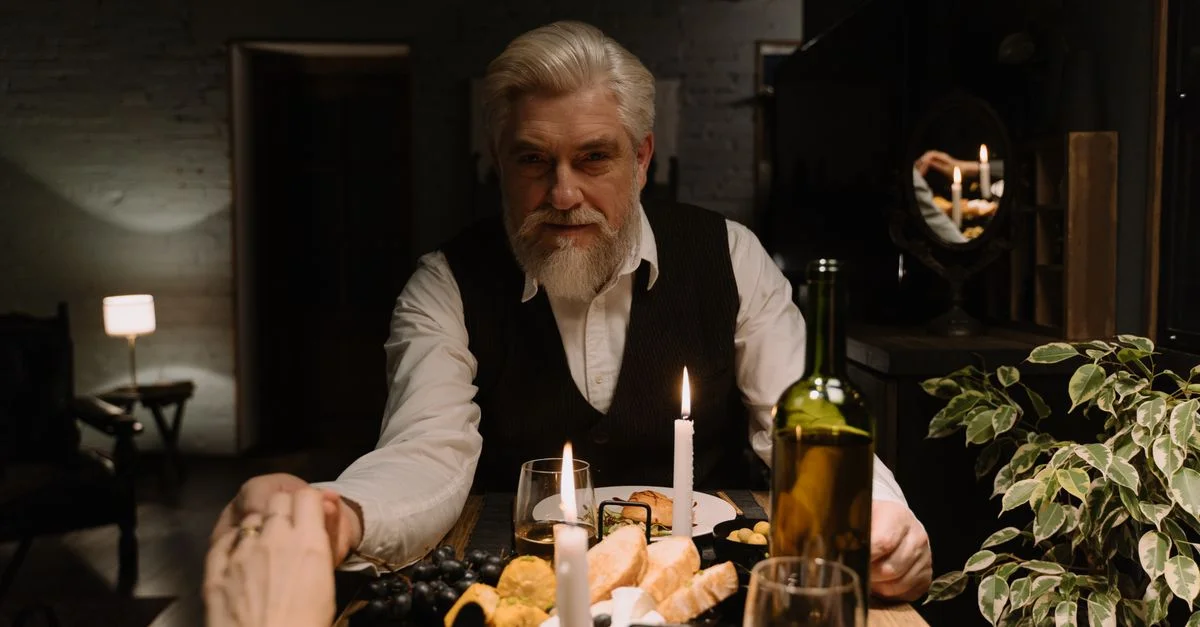 Un couple âgé partage un dîner romantique aux chandelles avec du vin et du pain dans un cadre chaleureux.