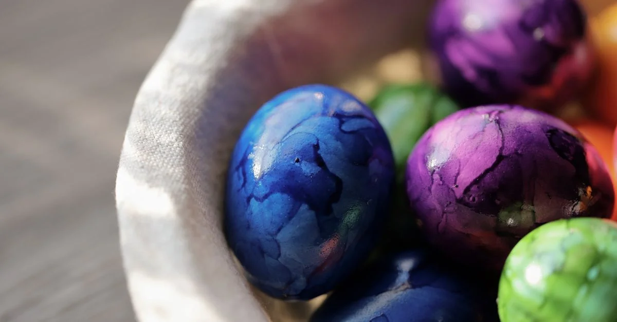 Gros plan sur des œufs de Pâques marbrés colorés dans un panier doux, capturant l'esprit des fêtes de printemps.