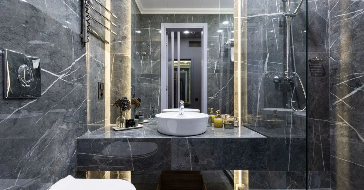 Salle de bain moderne luxueuse avec des murs en marbre, des appareils élégants et un éclairage d'ambiance.