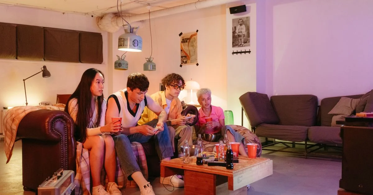 Groupe d'amis divers profitant des jeux vidéo dans un cadre confortable de salon.