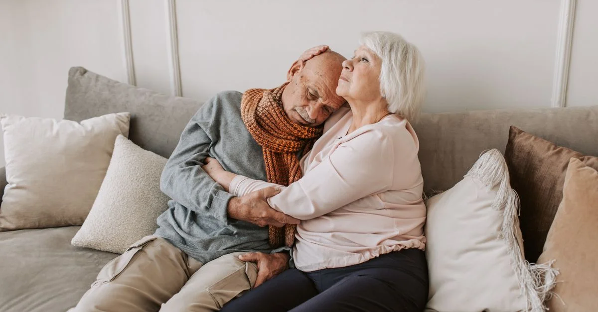 Un couple âgé affectueux assis ensemble sur un canapé confortable, montrant de l'amour et des soins.