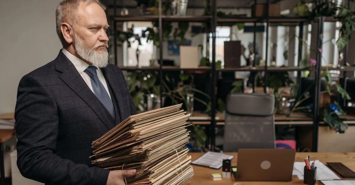 Un homme d'affaires senior tenant des dossiers dans un bureau moderne, incarnant le dévouement et le professionnalisme.
