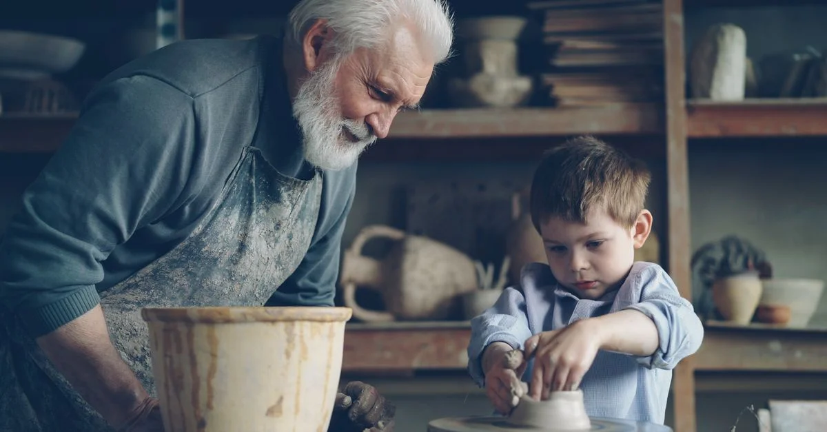 Un grand-père enseigne la poterie à son petit-fils dans un atelier de poterie créatif.