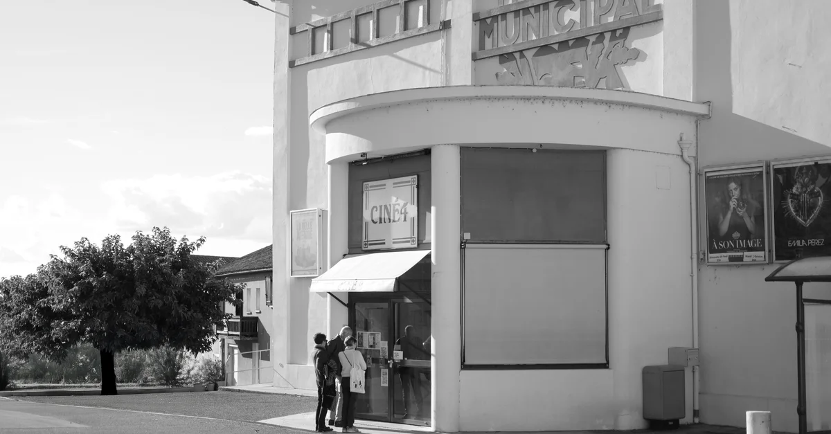 Entrée de théâtre rétro avec des spectateurs en noir et blanc, évoque une ambiance cinématographique classique.