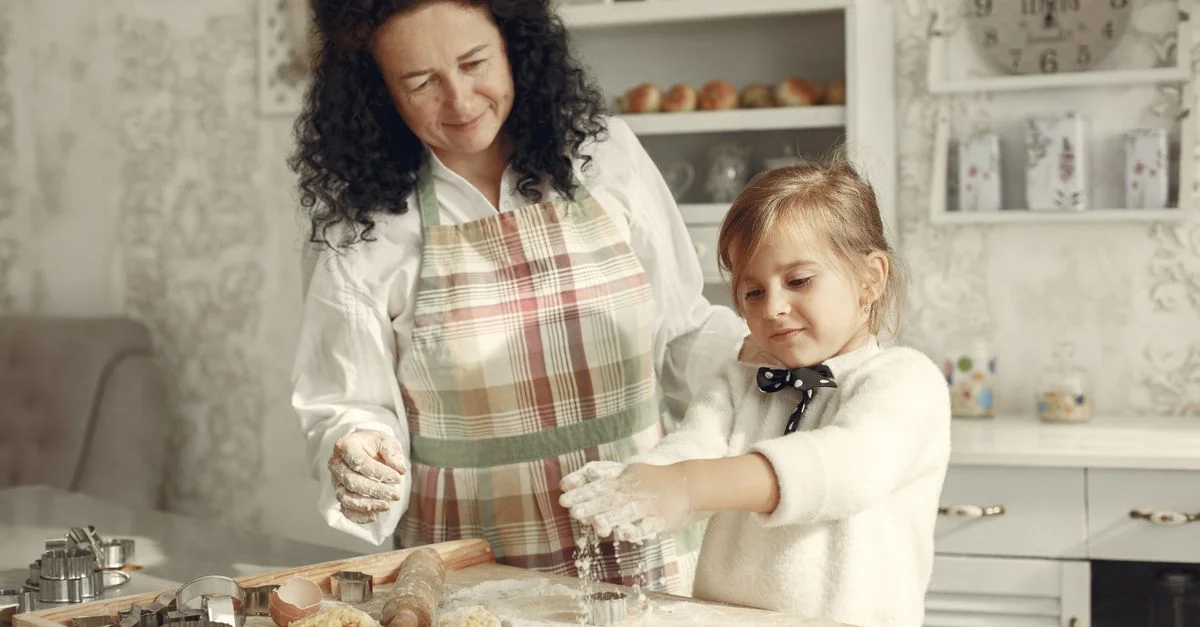 Un moment joyeux d'une grand-mère et de sa petite-fille en train de cuire des cookies dans une cuisine chaleureuse.