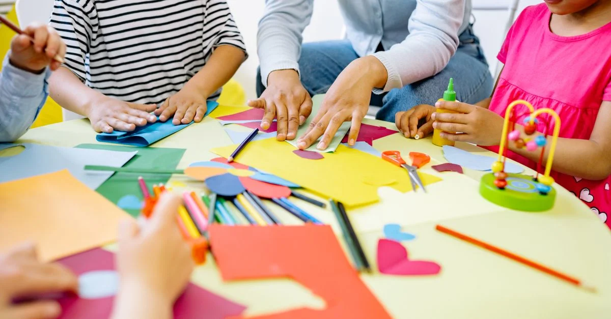Groupe d'enfants divers profitant d'activités artistiques créatives dans une salle de classe dynamique.