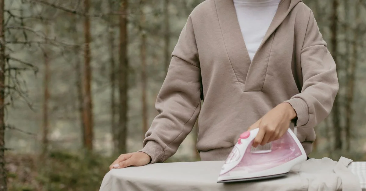 Une femme repasse une chemise sur une planche dans le cadre paisible d'une forêt.