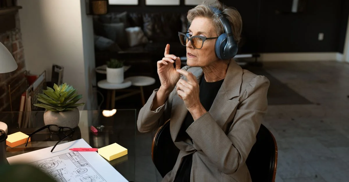 Femme senior dans un cadre de bureau, portant des écouteurs et s'engageant dans une communication audio.