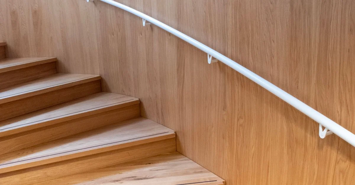 Escalier minimaliste en bois avec rampe blanche, offrant un cadre intérieur chaleureux et élégant.