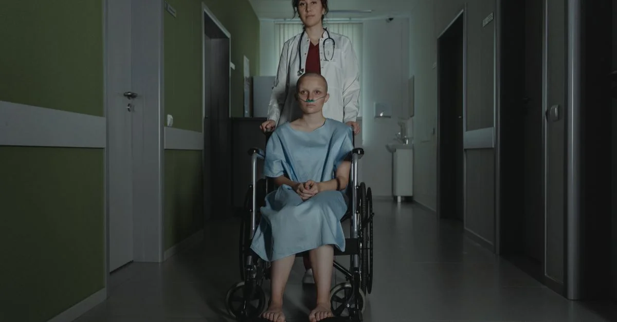 Médecin aidant une patiente féminine dans un fauteuil roulant dans un couloir d'hôpital mal éclairé.