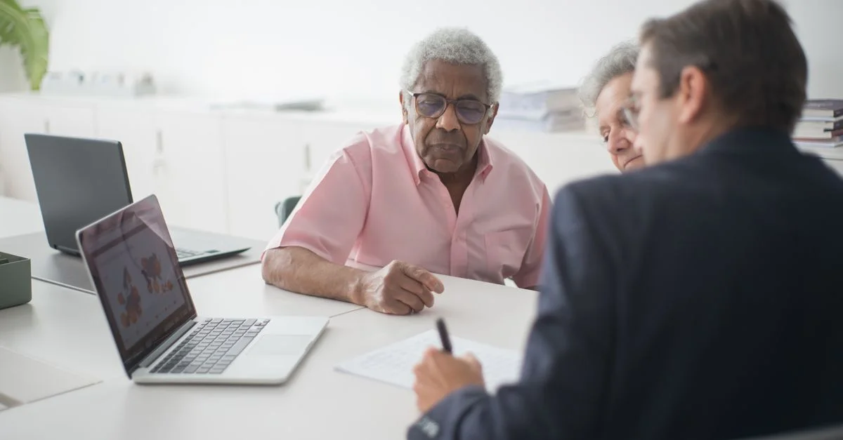 Couple senior discutant des options d'assurance avec un consultant dans un bureau.
