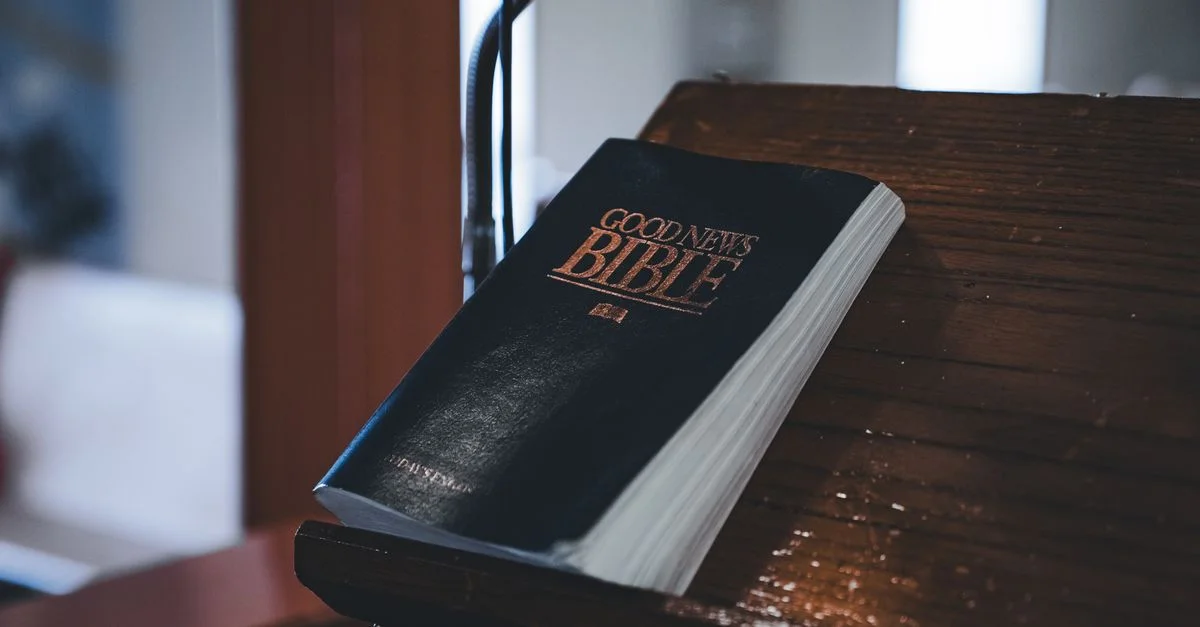 Gros plan sur la Bible des Bonnes Nouvelles reposant sur un pupitre en bois, idéale pour des thèmes religieux.