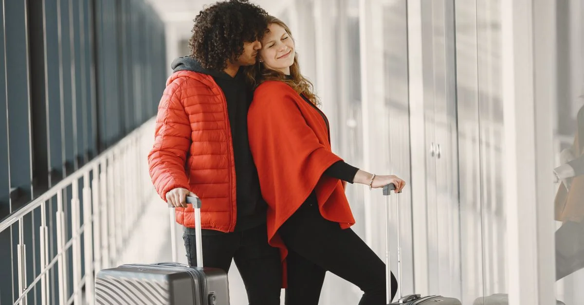 Couple souriant se tenant avec des bagages dans un couloir d'aéroport, profitant de leur voyage.