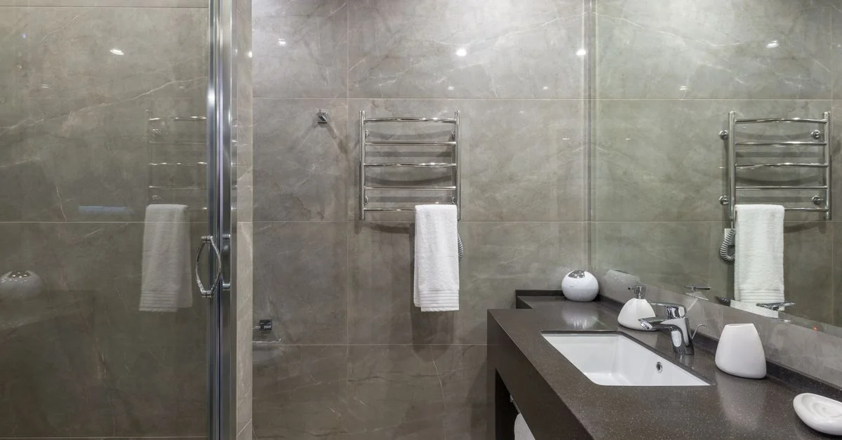 Salle de bains élégante et contemporaine avec murs en marbre, douche en verre et accessoires stylés.