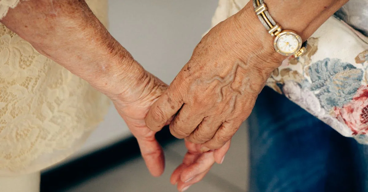 Gros plan sur des mains âgées se tenant, symbolisant soin et compagnie.
