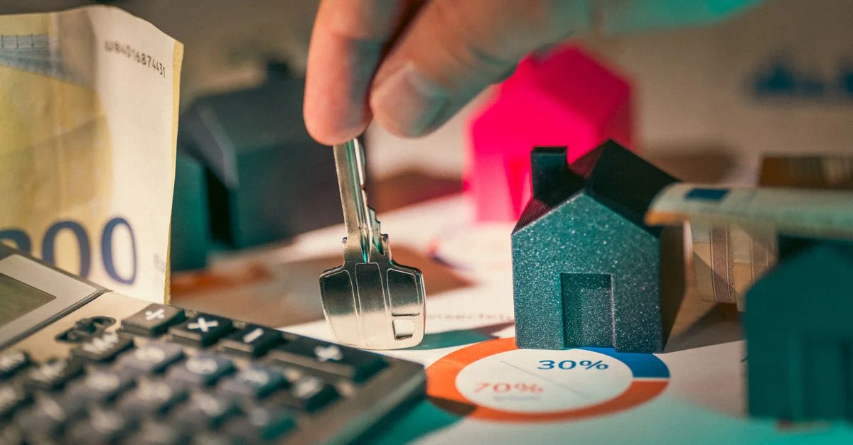 Un gros plan sur la planification financière immobilière avec des clés, une calculatrice et de l'argent.