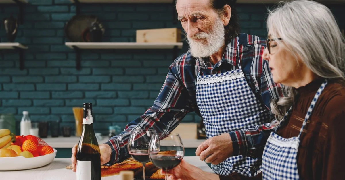 Couple senior partageant du vin et de l'affection dans une cuisine chaleureuse et accueillante.